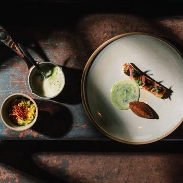 🌿Le végétal, autrement
Un légume peut raconter une histoire.☘

Celle d’un producteur local.  D’une récolte au bon moment. D’un geste précis en cuisine.

À Bossimé, le végétal occupe le cœur du menu, avec caractère et élégance

POIREAU - HERBES - FEU
On débute par un bouillon chaud, travaillé comme un dashi et infusé à la spiruline de Gaume. Il est accompagné d’un condiment de poireau rôti à la flamme, relevé d’anchois et d’ail confit, ainsi que de poireaux sautés.
On poursuit avec un poireau cuit à basse température puis flamé, décliné en
contrastes : cœur tendre, bords caramélisés et notes fumées. Un condiment
herbacé de persil et livèche, relevé d’oignon, raifort et piment d’Espelette, apporte
fraîcheur et caractère. Une texture de pain torréfié et une émulsion d’herbes
montée au beurre noisette qui vient arrondir l’ ensemble.

Pain
“flat bread” & beurre paprika fumé

PRODUCTEUR:
@jardindemimi , @SpirulinedeGaume, Ferme de Bossimé
ACCORD VIN:
Côtes du Rhône Villages Blanc 2024 – Domaine Saint-Vincent

Et si vous redécouvriez l’hiver à travers lui ?

Réservez votre table. Le reste, on s’en occupe.