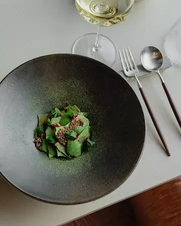 Crab gently cooked in aromatic broth, served with sea urchin and Belgian Crémant sabayon, a cardamom fromage blanc granita, and delicate parsley tuile 🌱