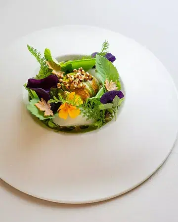 Peas and tagetes from Perma-Project farm in La Hulpe, paired with courgette flowers stuffed with squid and black sesame. Finished with a pea pod jus infused with tagetes, a whey foam, and fermented asparagus juice 🌱