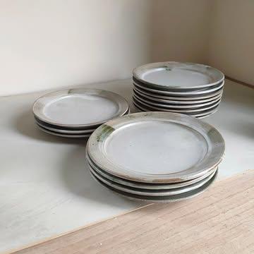 Rimmed plates for a new project opening in August in Tuscany. 
I would love to document the process a little more deeply but recording & editing it all are other skills to develop. 
🌿
If you swipe, you can see the Oribe wood ash glaze before the firing: a muddy, difficult to apply substance turning dark, spotted, crackled green. 
I don't use a stamp but I rather sign my plates by hand, as a free gesture - when are we still handwriting these days?
.
If you plan a trip to Tuscany, keep an eye on @land_restaurant_eb by @bl_enrico. 
The whole ecosystem around the restaurant is taking shape and it will be a joy to know my ceramics in this serene and beautiful environment. 
.
Thank you Enrico for your trust. ✨
.
{FR}
En route pour la Toscane 🌿
Pas moi - même si j'aimerais beaucoup y faire une pause estivale- mais ces assiettes à bord large avec une touche de vert Oribe. 
.
Si vous faites défiler, vous verrez quelques étapes de leur façonnage. L'émail avant sa transformation par le feu, le Tetris dans le four, la signature à main levée. Trace de l'humain derrière l'objet. 
.
Si vous passez dans cette belle région de l'Italie, faites une étape chez @land_restauranr_eb ~ ils ouvrent tout bientôt.