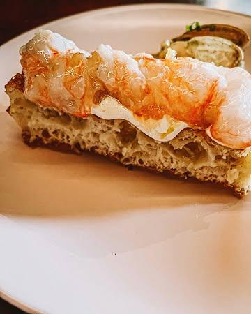 x @elders.gent - BIJNA 3. 

🧑‍🍳 @tompauwelyn 
🍇 @romydeconinck 
❤️ @thomas_bontinck @clarafrancoiske @angeliquebeyens 

Voorheen kreeg Milo mij nooit, maar dan ook echt nooit, mee naar de markt op het Van Beverenplein. Maar nu? Nu kunnen we spreken van een pre-Elders/Anders tijdperk, en een post.

Voorheen is niet meer nu, de keren dat ik naar de markt vlieg, zijn mijn aantal vingers allang voorbij. Een perfecte zondag wordt nu gedefinieerd, geschapen en vervolledigd door hén.

Tom en Romy hebben iets uniek gecreëerd. Uiteraard is het vééééél meer dan een zondags uitje met wijn, al dan niet à la carte uitlevingen, cocktails en tipsy naar huis stappen.

Nee, ik schrijf zogezegd niet over de pita, of de wafels met langoustines of coquilles. Niet over hoe kiezen bij de voor- en hoofdgerechten steeds weer een beetje verliezen is.
- Eerlijk hoe kan je nu kiezen tussen: Varkensspiering, wortel, gerookte appel;  gekonfijte skrei, kooltjes, oester, weisaus of rissoto van zonnebloempit, aardpeer, burrata, eerlijk ik krijg er weer stress van - 

Niet over het staren naar dat powerkoppel dat levensvreugde uitstraalt en een stukje foodiehemel personifieert. Niet over de eerste bezoekjes van Charlie, Bonnie en binnenkort Donna die blijven en zullen blijven hangen. Noch de duizenden selfies in het toilet (een ware collectie op zich). 

Ik schrijf zogezegd niet over de overheerlijke, zelfgemaakte pasta’s: zoals spaghette alla chitarra met oa maitake of parpadelle al nero. Of zwijg ik dan maar over die aubergine met die gerookte dooier, holy moly.

Maar zie mij hier nu schrijven en nu ik mij geen pre-tijd meer voorstellen kan, maakt de gedachte aan een non-gedachte mij wel gelukkig.

(Bijna) 3 jaar Elders. 3 jaar happy Belly.

#elders #gent #gent #belly #lolosbelly #bijna3 #liefde #food #altijdhonger #charlieweet #vanbeverenplein
