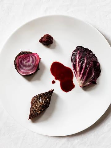 Geroosterde hazenrug, gekonfijte -billen met hazenpaté, tartaar en een met bietenmelasse verrijkte jus. Met palmkool, groene linze miso en eekhoorntjesbrood crème gevulde radicchio.

—————-

Roasted saddle of hare, confit leg with hare pâté, tartare, and a broth enriched with beet molasses. Served with palm kale, green lentil miso, and radicchio filled with porcini cream.